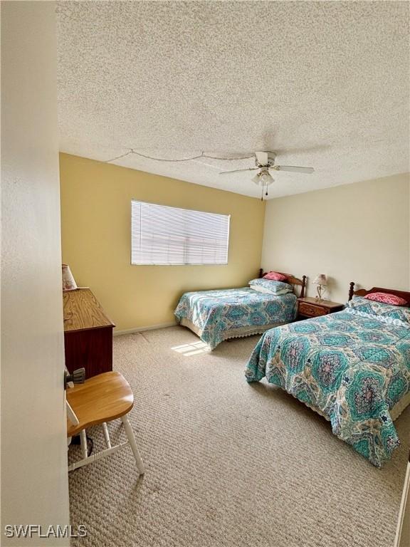 carpeted bedroom with a ceiling fan and a textured ceiling