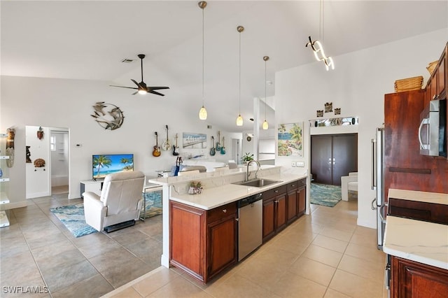 kitchen with open floor plan, high vaulted ceiling, appliances with stainless steel finishes, and a sink