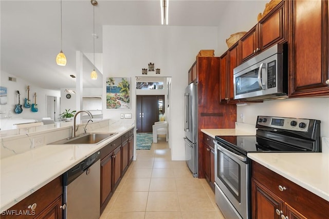 kitchen with light tile patterned floors, light countertops, hanging light fixtures, appliances with stainless steel finishes, and a sink