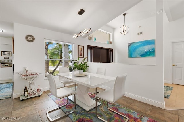 tiled dining area with high vaulted ceiling, baseboards, and visible vents