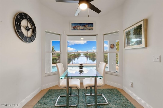 dining area with a water view, a ceiling fan, and baseboards