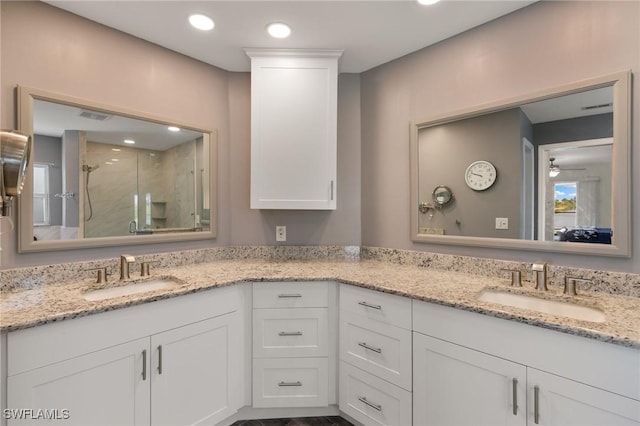 bathroom featuring double vanity, a stall shower, and a sink