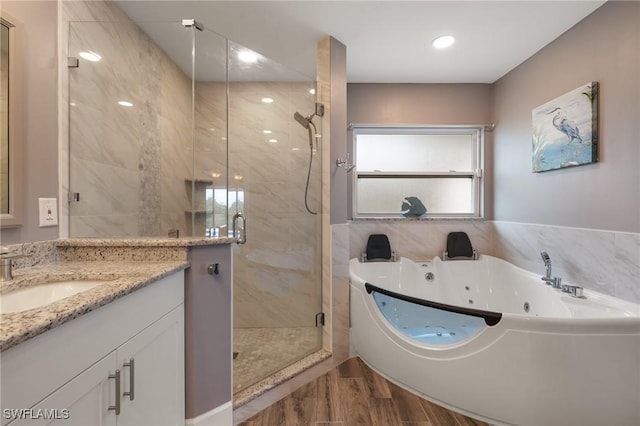 bathroom featuring a stall shower, vanity, a tub with jets, and wood finished floors