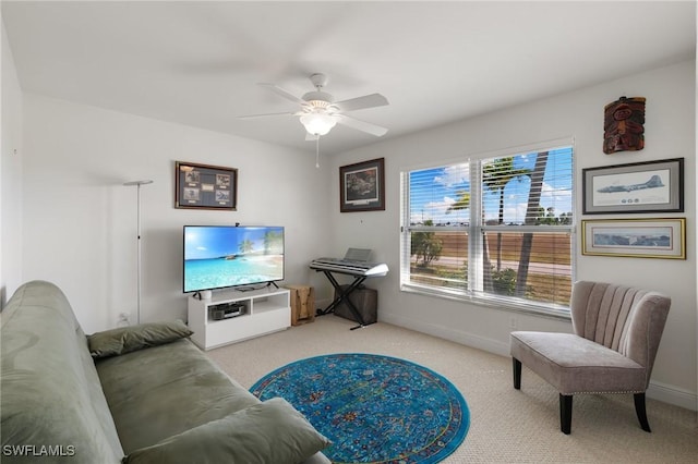 living area with baseboards, a ceiling fan, and light colored carpet