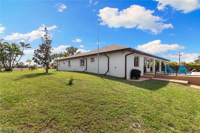 back of property with a yard and stucco siding