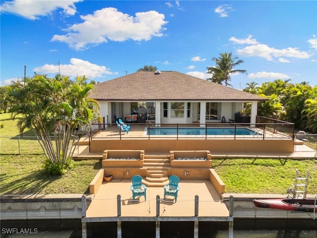 rear view of property featuring a patio area, fence, a fenced in pool, and roof with shingles