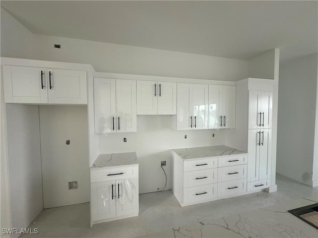 kitchen featuring light stone countertops and white cabinets