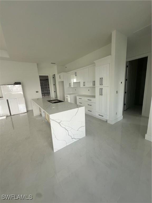 kitchen featuring baseboards, white cabinets, a kitchen island, light stone countertops, and marble finish floor