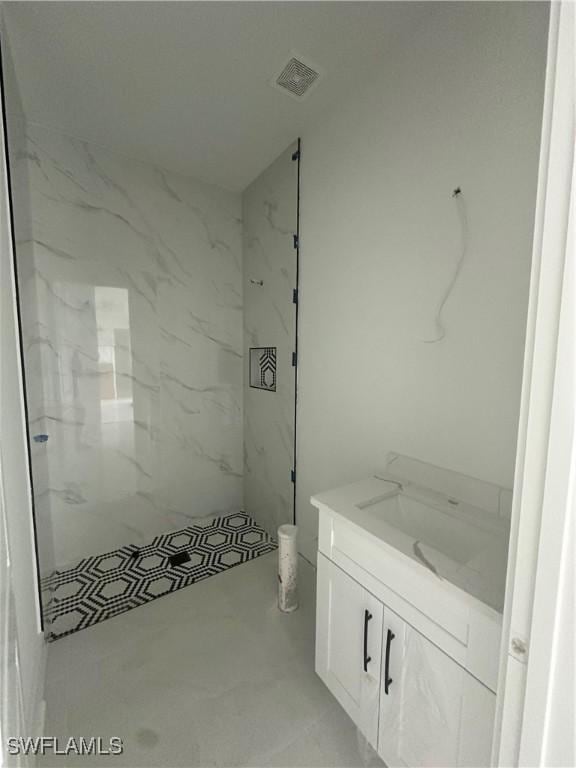 full bath featuring a marble finish shower, visible vents, and vanity