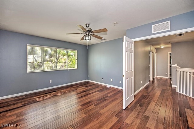 empty room with wood finished floors, visible vents, and baseboards