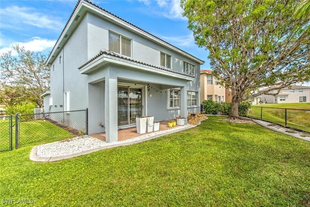 back of house with a gate, stucco siding, a lawn, and fence