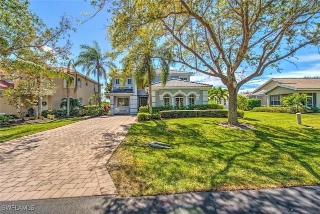 mediterranean / spanish-style house with a tile roof, decorative driveway, and a front yard