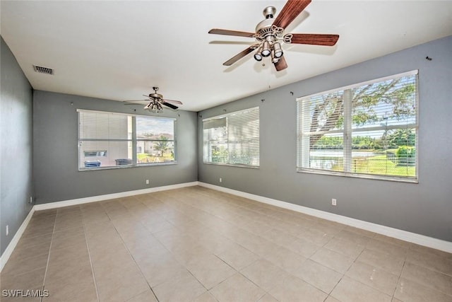 spare room with ceiling fan, light tile patterned flooring, visible vents, and baseboards