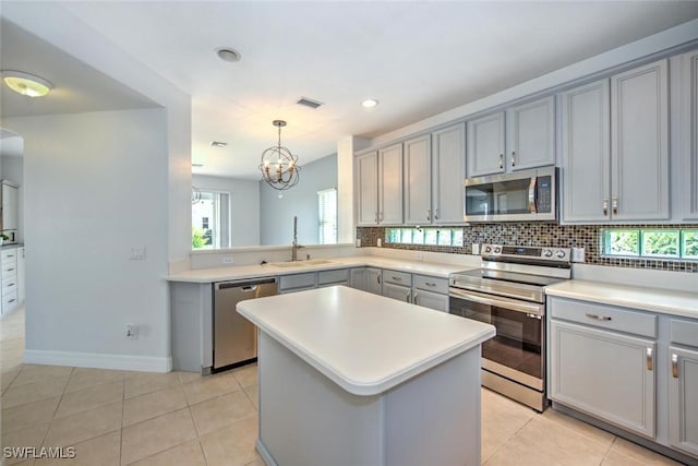 kitchen with gray cabinetry, a sink, visible vents, appliances with stainless steel finishes, and decorative backsplash