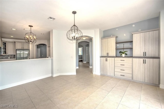 kitchen featuring arched walkways, open shelves, light brown cabinets, a chandelier, and fridge