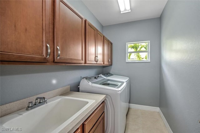 washroom featuring cabinet space, light tile patterned floors, baseboards, washer and dryer, and a sink