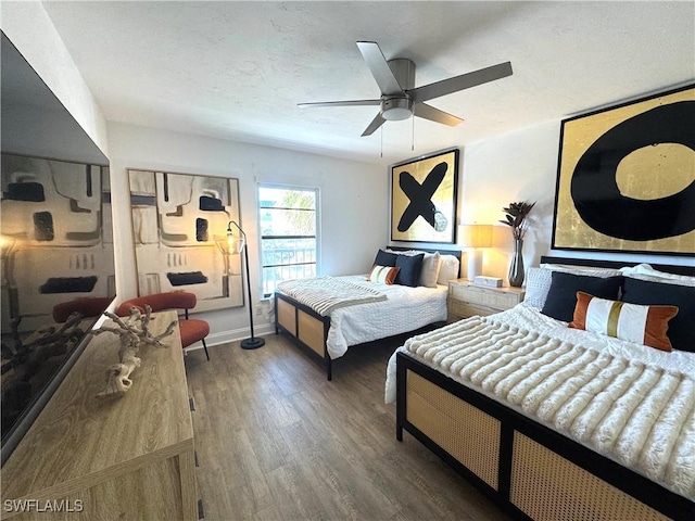 bedroom featuring a ceiling fan, a textured ceiling, baseboards, and wood finished floors