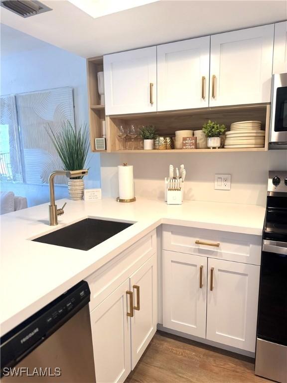 kitchen featuring open shelves, a sink, white cabinets, and stainless steel appliances