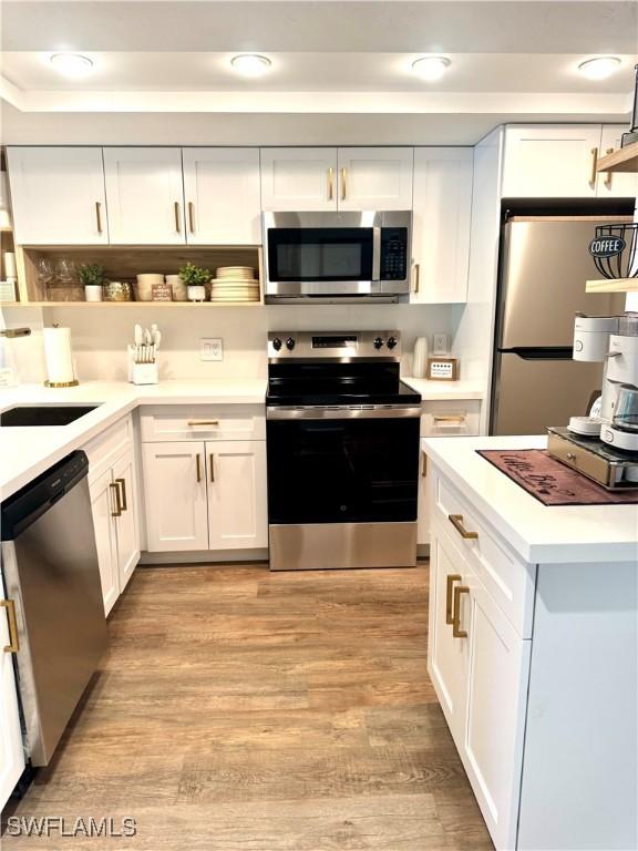 kitchen featuring open shelves, light countertops, appliances with stainless steel finishes, white cabinets, and a sink