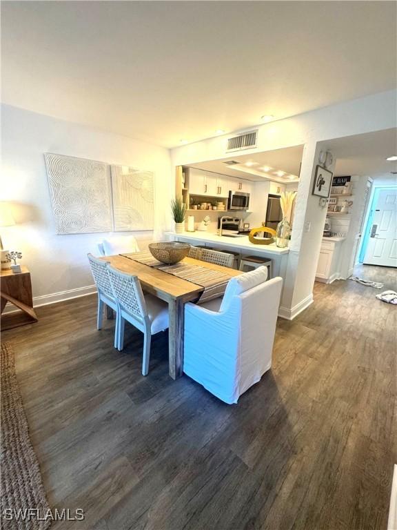 dining space with baseboards, visible vents, and dark wood-type flooring