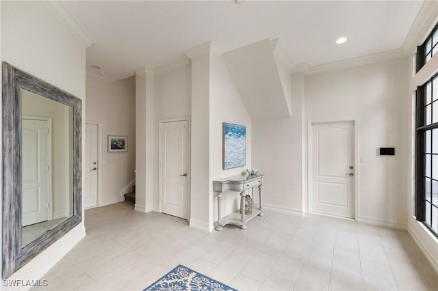 foyer entrance featuring stairway, baseboards, crown molding, and a towering ceiling