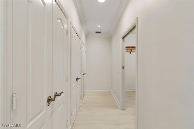 hallway with light wood-style flooring, visible vents, crown molding, and baseboards