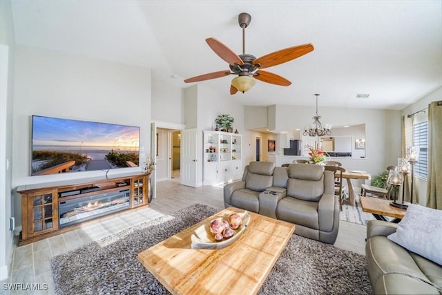 living area featuring ceiling fan with notable chandelier, high vaulted ceiling, wood finished floors, and visible vents