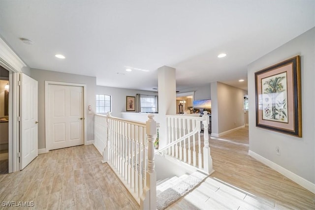 hall featuring light wood-type flooring, an upstairs landing, and recessed lighting