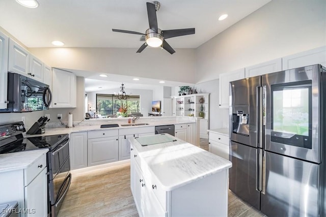 kitchen featuring lofted ceiling, a peninsula, black appliances, white cabinetry, and a sink