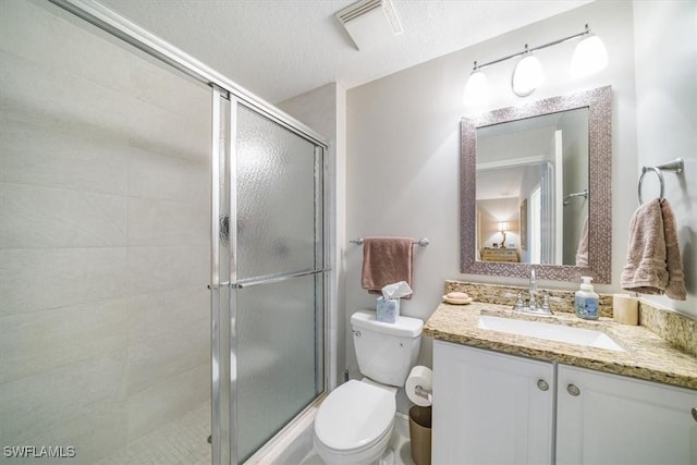 full bath with visible vents, toilet, a textured ceiling, a shower stall, and vanity