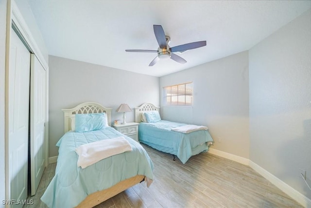 bedroom featuring ceiling fan, a closet, wood finished floors, and baseboards