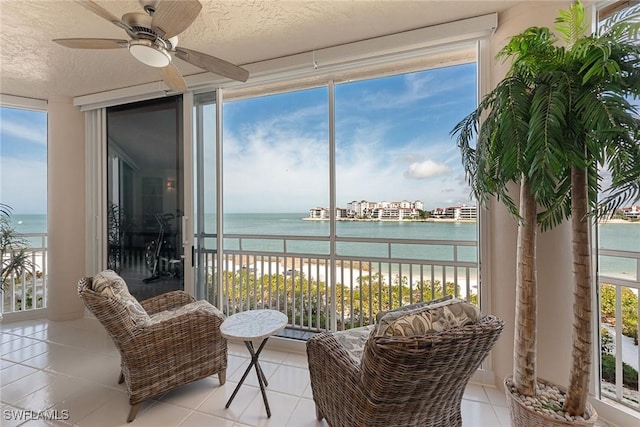 sunroom with a water view, plenty of natural light, and a ceiling fan