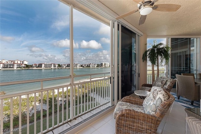 sunroom featuring ceiling fan and a water view