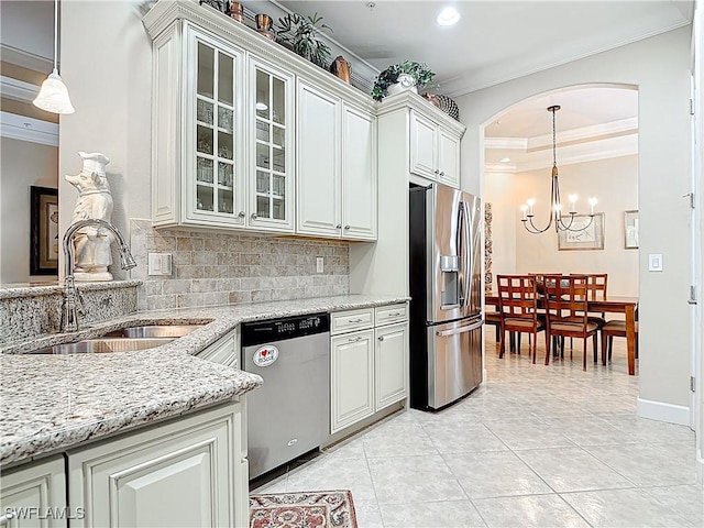 kitchen featuring tasteful backsplash, light stone countertops, stainless steel appliances, crown molding, and a sink