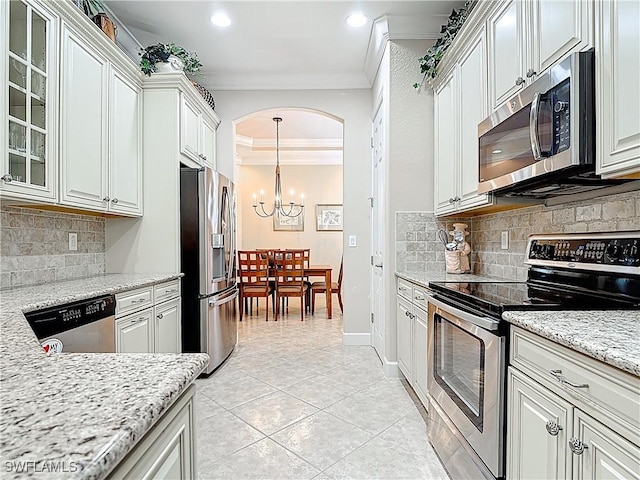 kitchen with arched walkways, a notable chandelier, crown molding, stainless steel appliances, and glass insert cabinets