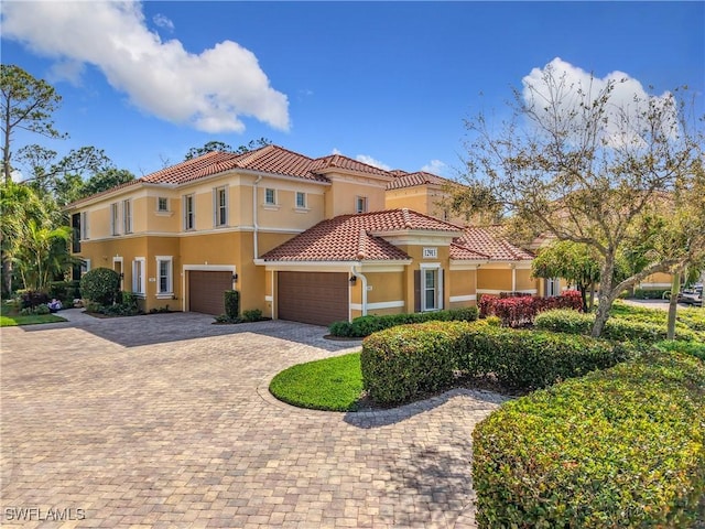 mediterranean / spanish-style home with a tiled roof, decorative driveway, and stucco siding