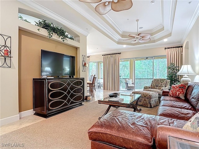 living area featuring a raised ceiling, a ceiling fan, ornamental molding, baseboards, and tile patterned floors