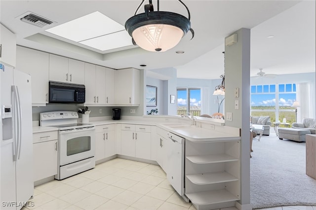 kitchen featuring light countertops, visible vents, open floor plan, a sink, and white appliances