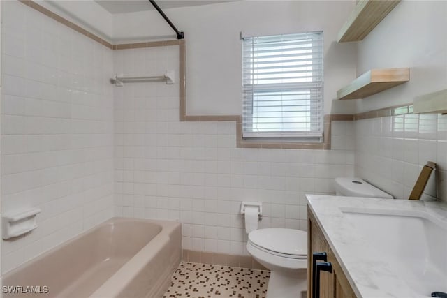 bathroom featuring toilet, tile patterned flooring, vanity, tile walls, and shower / bathing tub combination