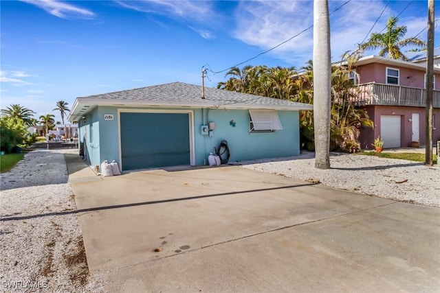 view of front of property with a garage, driveway, a shingled roof, and stucco siding