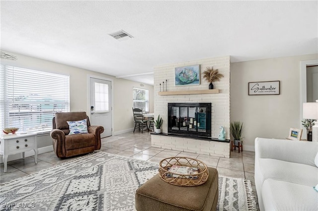 living area featuring a brick fireplace, baseboards, light tile patterned floors, and visible vents