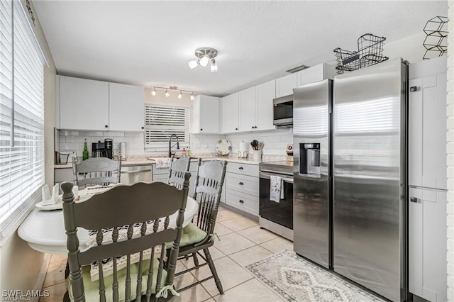 kitchen with appliances with stainless steel finishes, white cabinets, light countertops, and light tile patterned flooring