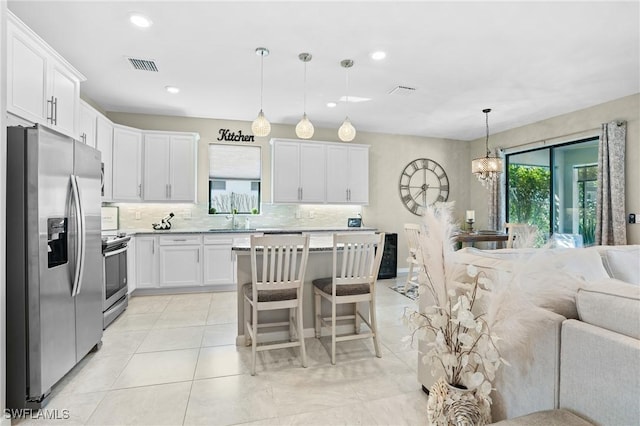 kitchen with visible vents, a sink, appliances with stainless steel finishes, white cabinetry, and tasteful backsplash