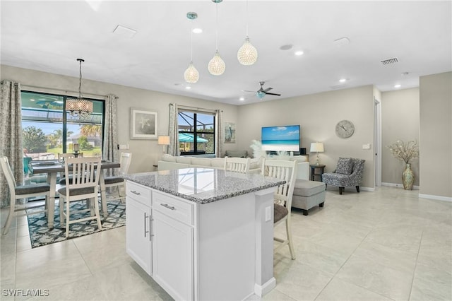 kitchen with hanging light fixtures, visible vents, white cabinetry, and light stone countertops