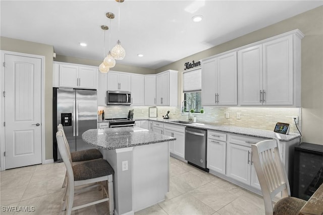 kitchen with a sink, light stone counters, white cabinetry, and stainless steel appliances