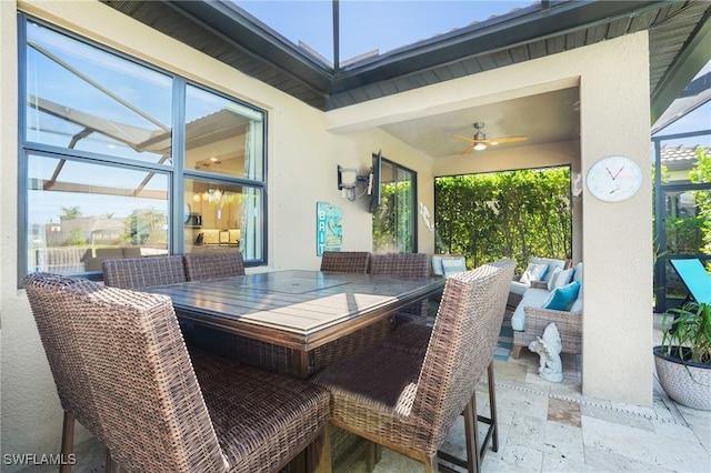 view of patio with outdoor dining area, an outdoor hangout area, glass enclosure, and a ceiling fan