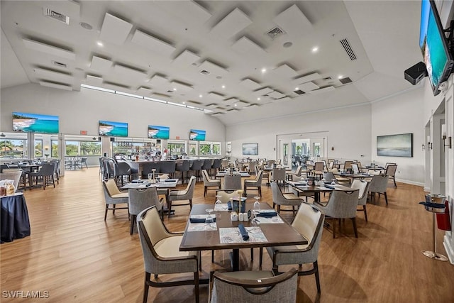 dining space featuring high vaulted ceiling, light wood-type flooring, and visible vents