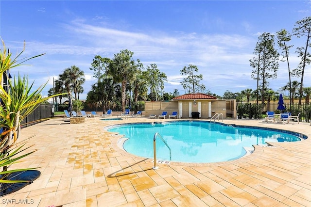 pool with a patio area and fence