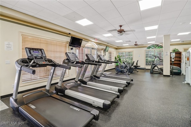 workout area featuring a drop ceiling, ceiling fan, and baseboards