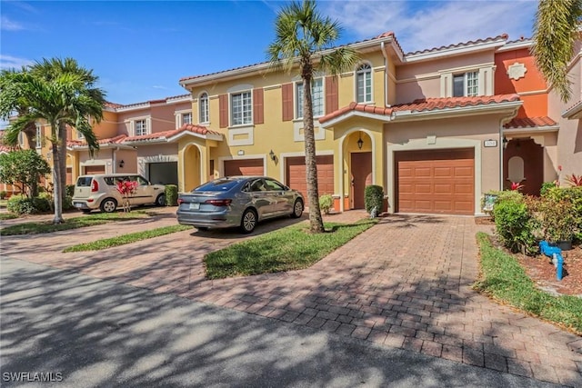 view of front of property featuring driveway, an attached garage, a tile roof, and stucco siding